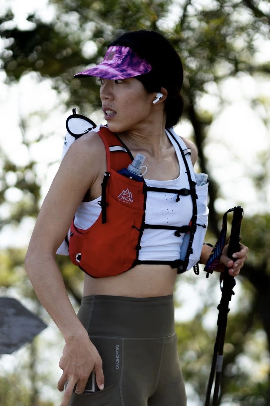 Ria Xi standing on a mountain trail at golden hour, looking toward the horizon